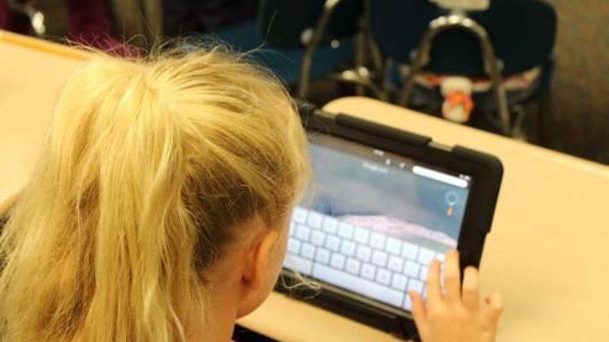 Una nena utilitzant un Ipad en una classe.