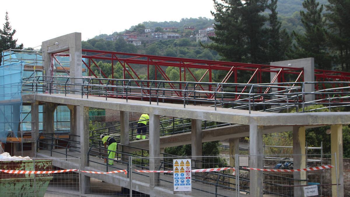 Dos operarios rematan la rampa de acceso desde el núcleo de Caborana a la pasarela peatonal.