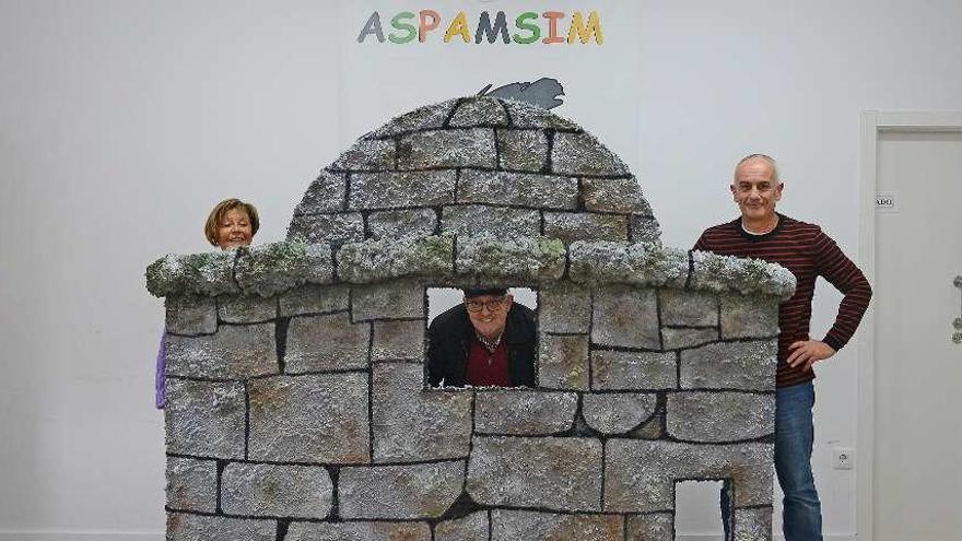 Arriba, el alcalde (centro) con Nonoi Pérez y Carlos Sotelo, en el decorado que representa a O Facho. A la izda., dos usuarios de Aspamsim en O Facho en la fotografía del calendario. // G.N.