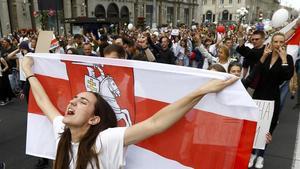 Una mujer con la antigua bandera nacional de Bielorrusia encabeza una marcha de protesta, este viernes en Minsk.