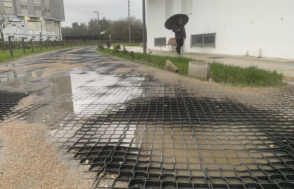 El nuevo firme de plástico en el acceso a los garajes, repleto de charcos, que ha generado muchas quejas.