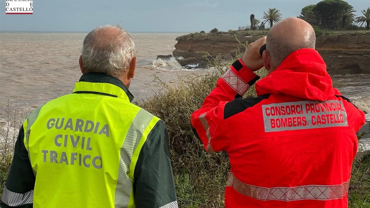 Un miembro de la Guardia Civil y del Consorcio Provincial de Bomberos observan el coche siniestrado en la playa del Triador de Vinaròs.