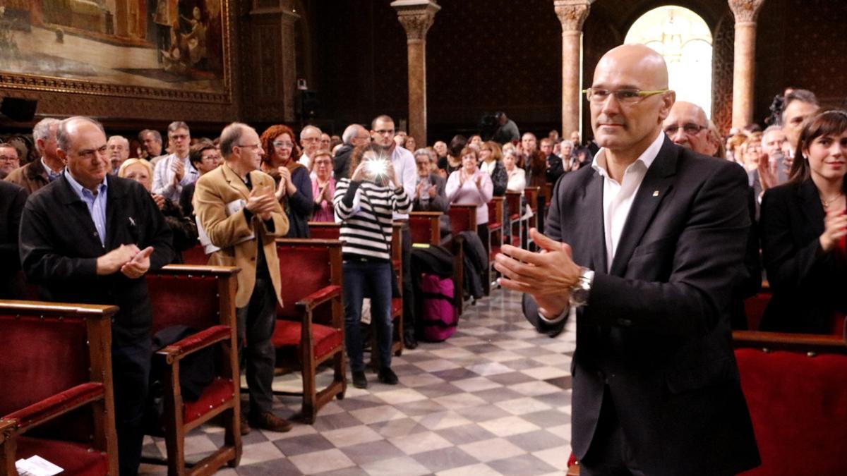 El 'conseller' Raül Romeva aplaude a los homenajeados en el acto de la Generalitat dedicado a los represaliados por la guerra civil y el franquismo, este domingo en el paraninfo de la UB.