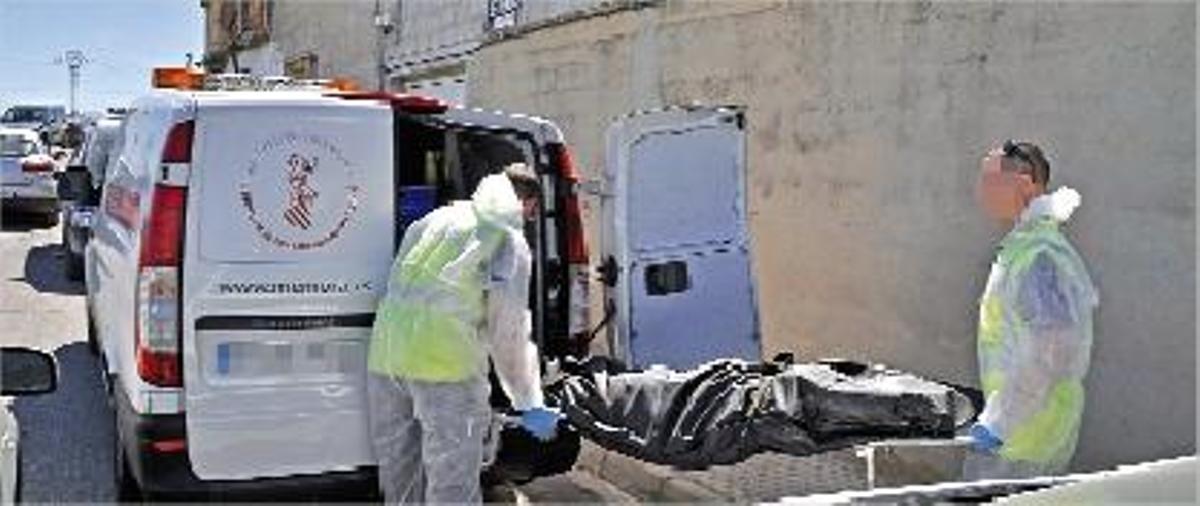 Dos operarios introducen el cuerpo de la víctima en el furgón.