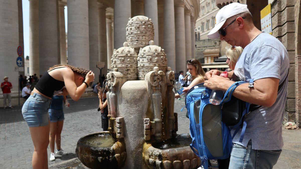 Varias persionas se refrescan en uan fuente en el Vaticano