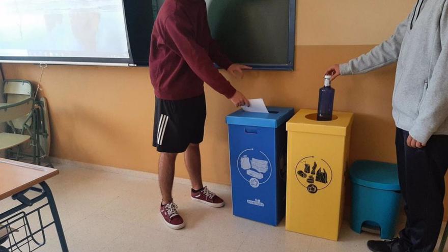 Dos alumnos reciclan residuos en una clase. | L.O.
