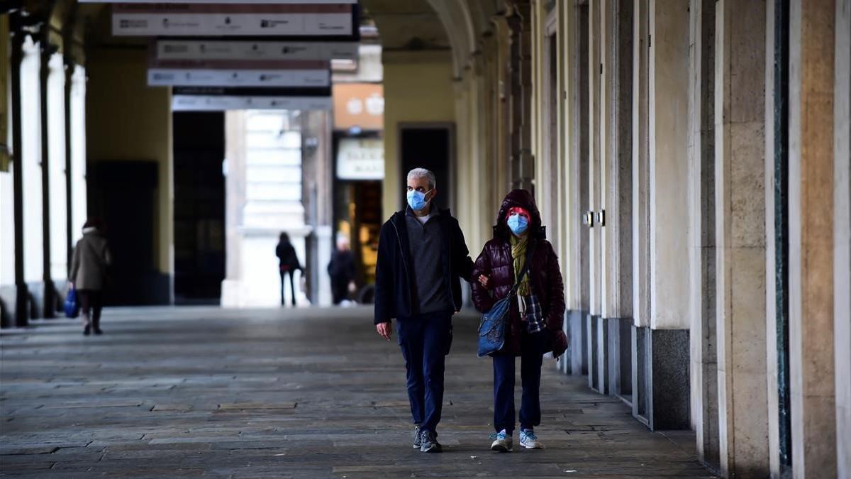 Dos personas con mascarilla caminan en una desierta plaza de San Carlo, este jueves en Turín.