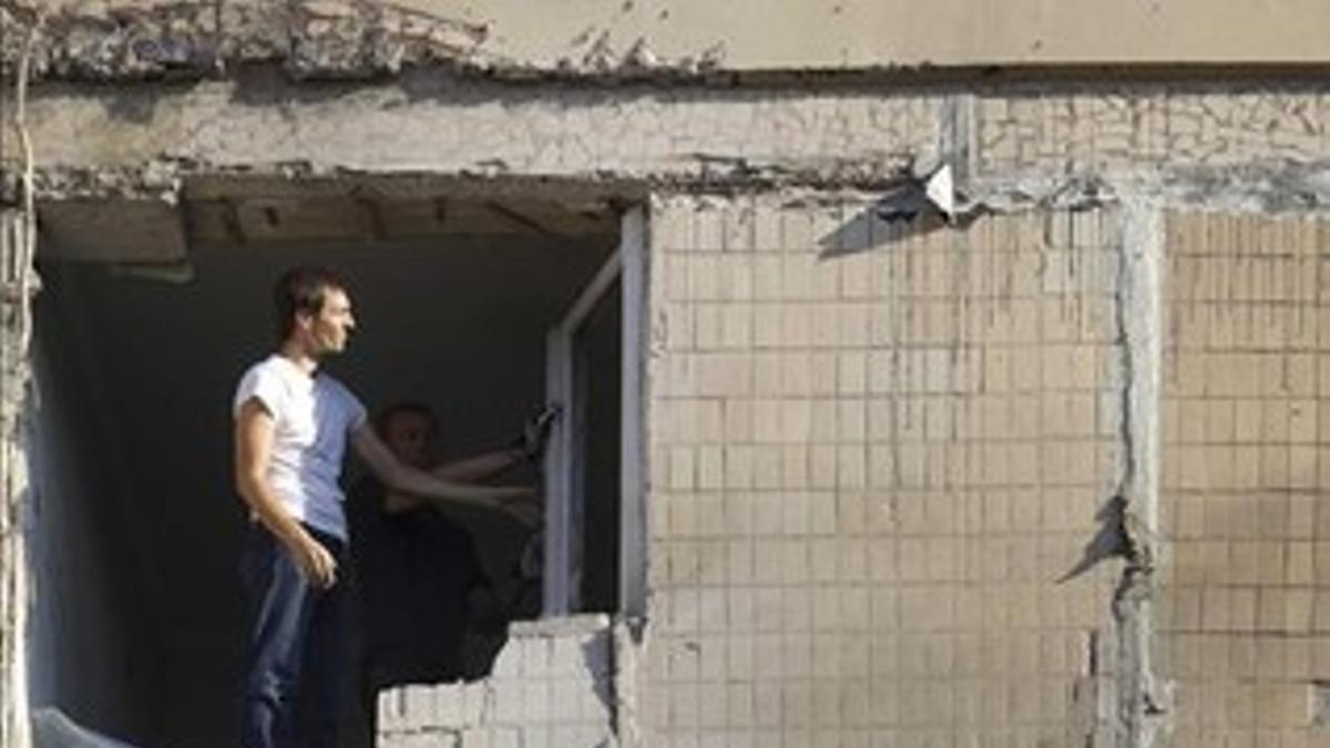 Un hombre mira el resultado del impacto de un obus sobre un edificio en Donetsk.