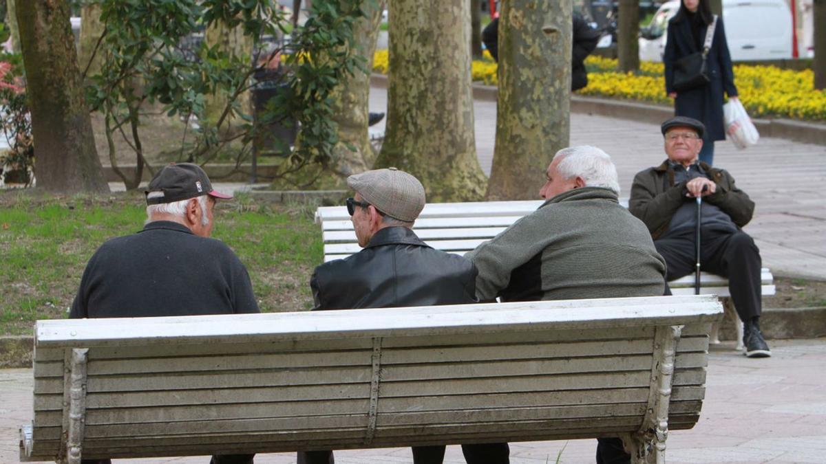 Un grupo de mayores en un banco en un parque de Ourense.