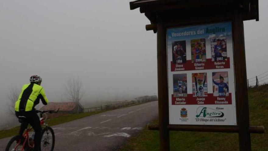 Un cicloturista transita junto a uno de los nuevos carteles que recuerdan a los ganadores en el Angliru.