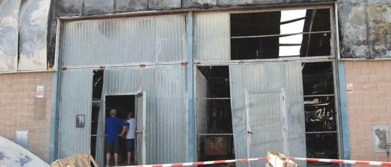 Varios afectados observaban ayer el interior de una nave con un perito de seguros.