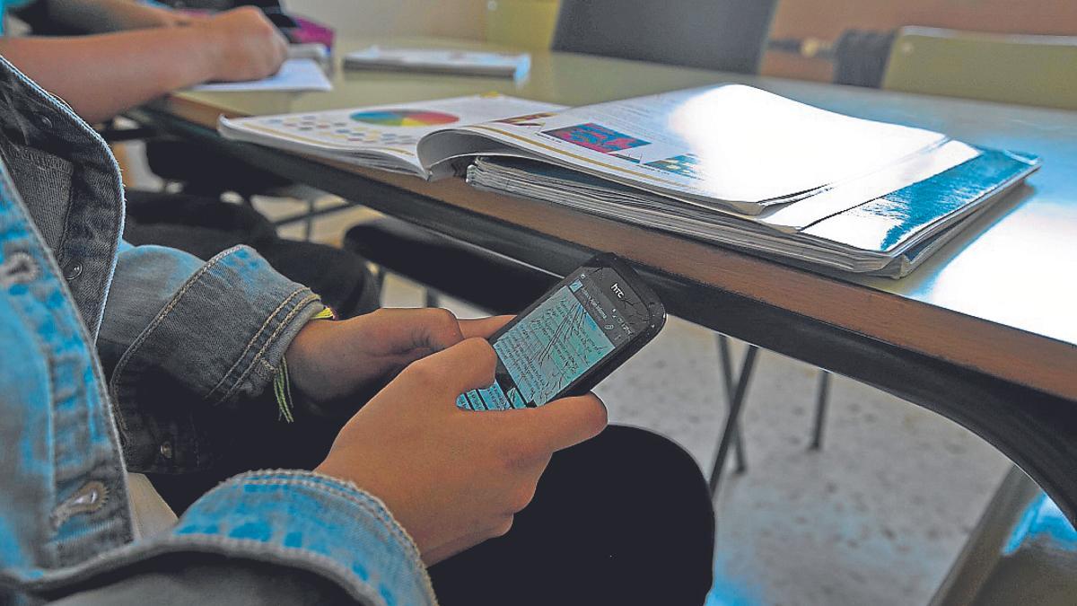 Imagen de archivo de un estudiante con el móvil en una clase.