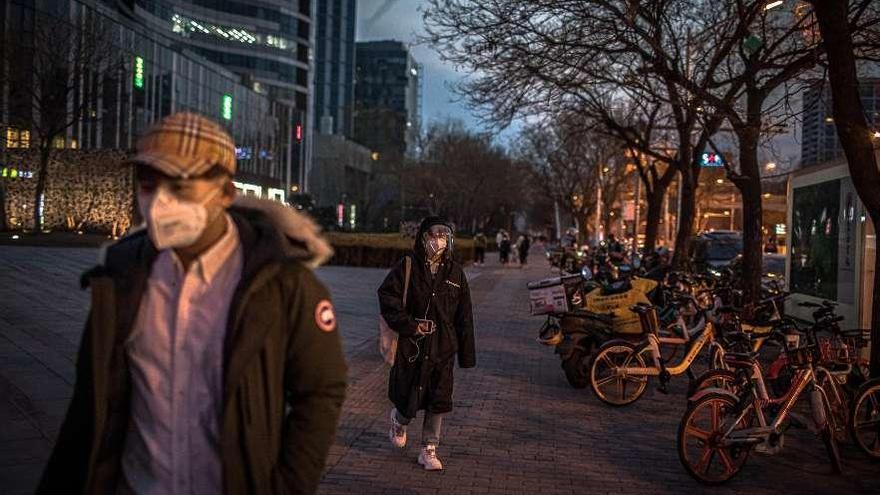 Habitantes de Biejing, en China, protegiéndose con mascarillas en un área residencial. // Efe