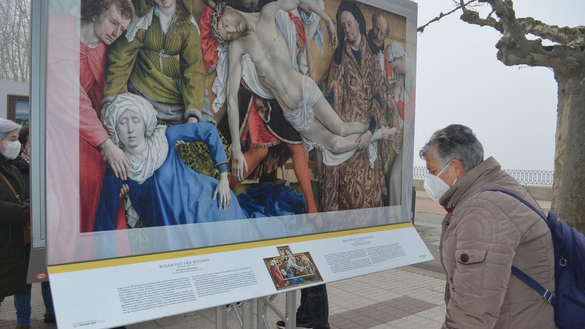 Una vecina de Benavente, observando la leyenda de una de las obras del Prado expuestas en Benavente. / E. P.