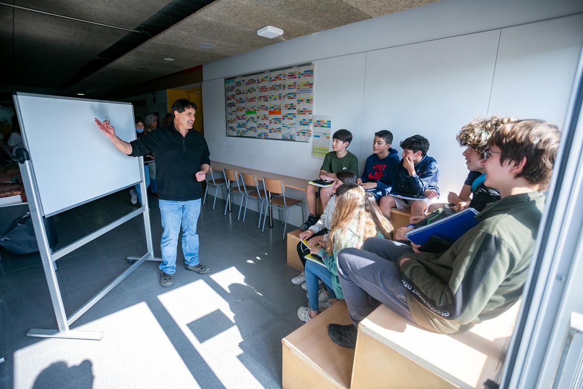 Un profesor atiende a un grupo de alumnos en unas gradas habilitadas en un pasillo del Instituto Montgròs de Sant Pere de Ribes