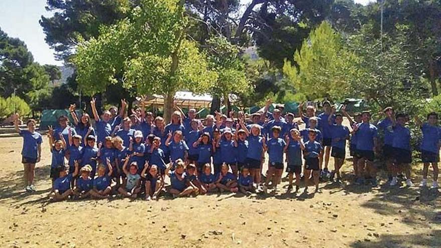 Un grupo de niÃ±os de un campamento de verano de AlcÃºdia saludando ante las tiendas.