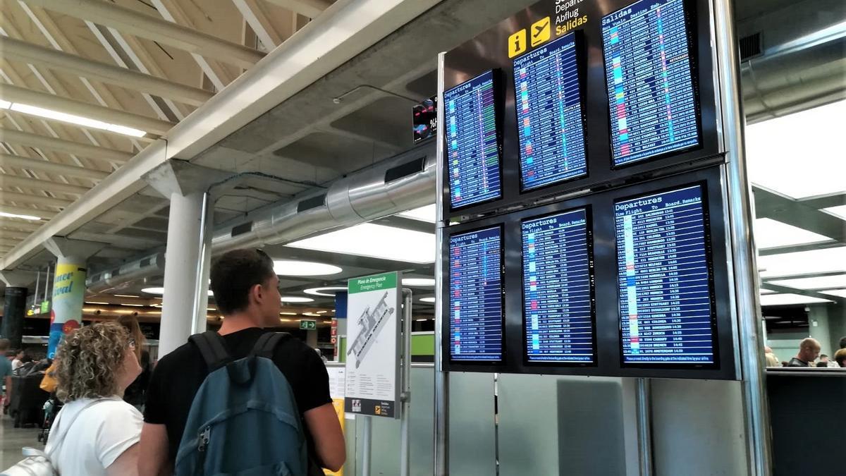 Archivo - Turistas comprueban la información de las pantallas de embarque en el aeropuerto de Palma.