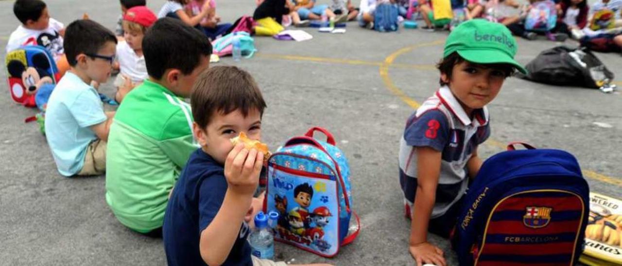 Un grupo de niños merienda en el campamento urbano de verano, en el colegio A Escardia. // Iñaki Abella