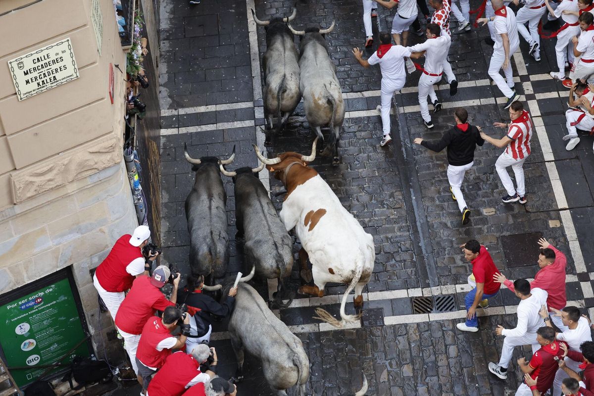 PAMPLONA, 12/07/2025.- Mozos perseguidos por los toros de la ganadería de José Escolar en el sexto encierro de los Sanfermines, este sábado en Pamplona. EFE/ Villar López
