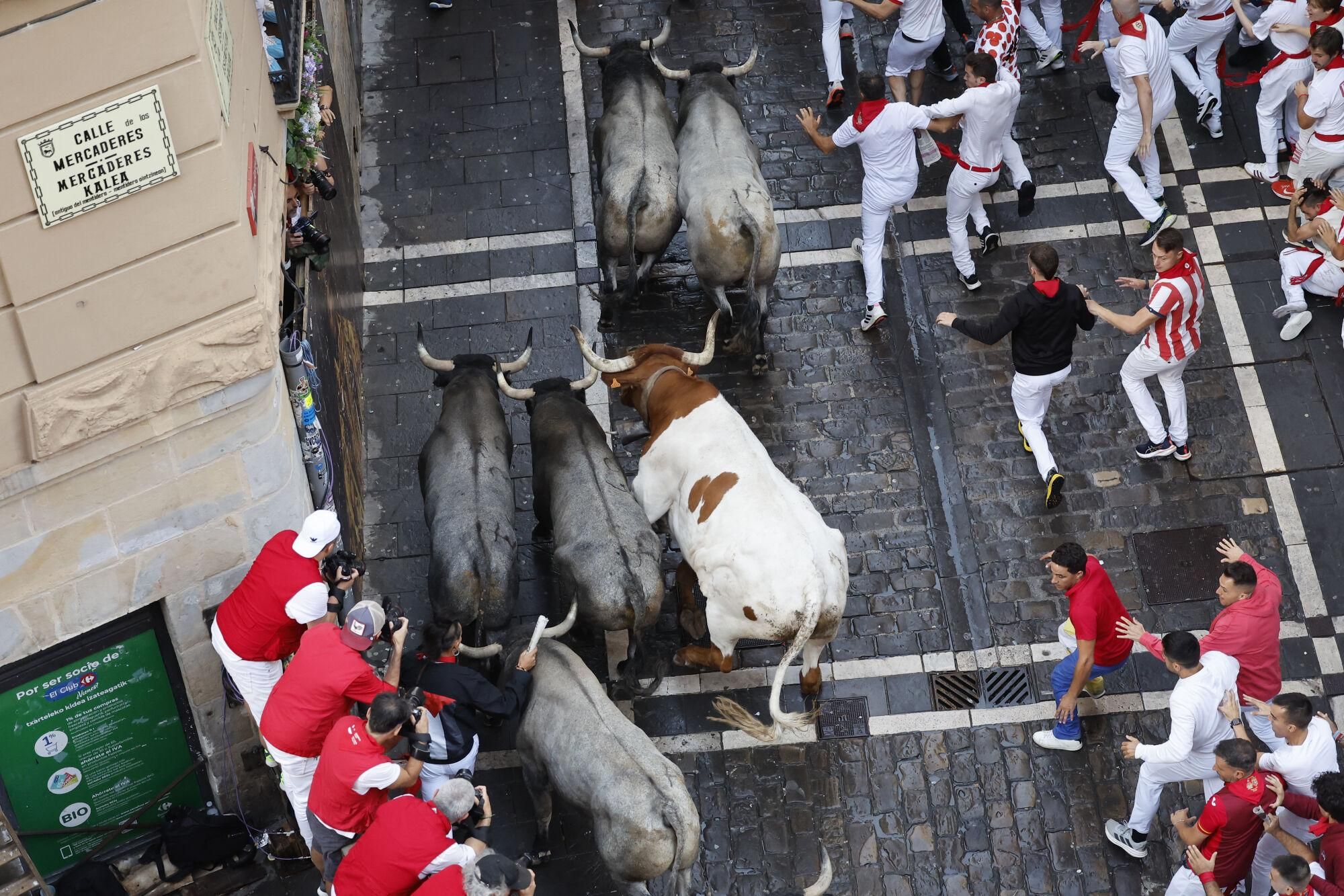 PAMPLONA, 12/07/2025.- Mozos perseguidos por los toros de la ganadería de José Escolar en el sexto encierro de los Sanfermines, este sábado en Pamplona. EFE/ Villar López