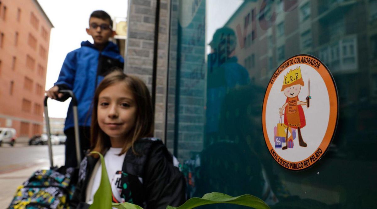 Arriba, Alfredo González y Ainhoa López, cola pegatina de Pelayín. A la izquierda, los escolares, nel quioscu Pili, xunto a Blenny Bautista. | J. Plaza
