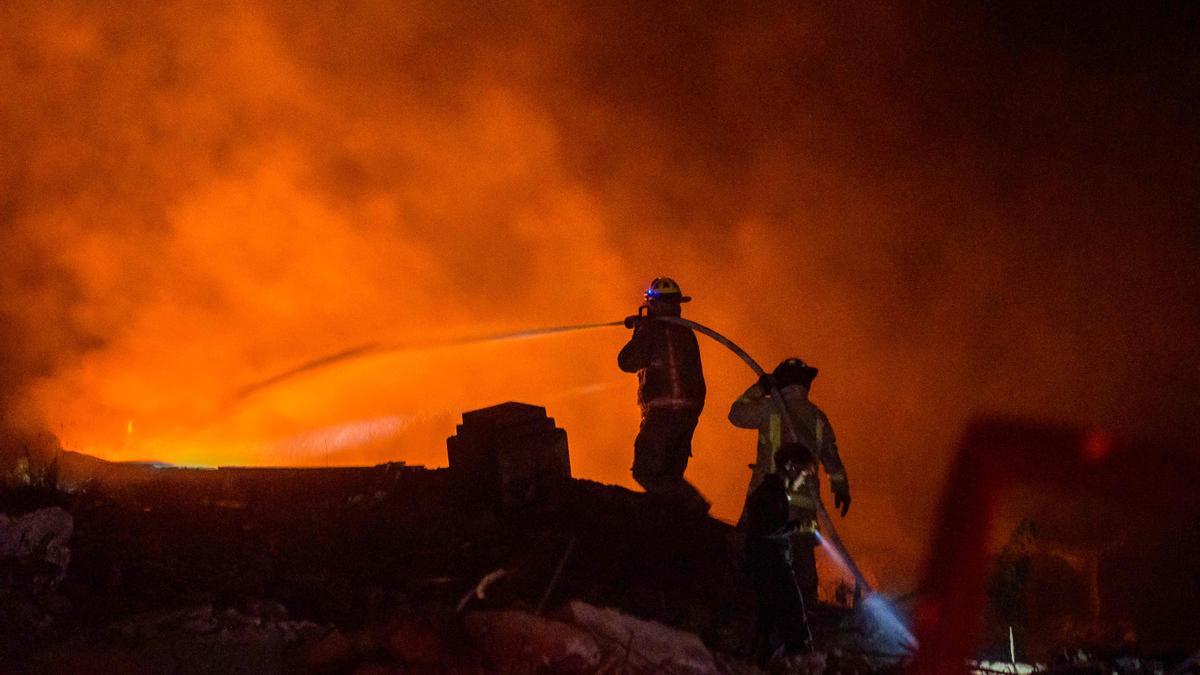 Los bomberos luchan por extinguir el incendio en una zona comercial de San Cristóbal, en República Dominicana.