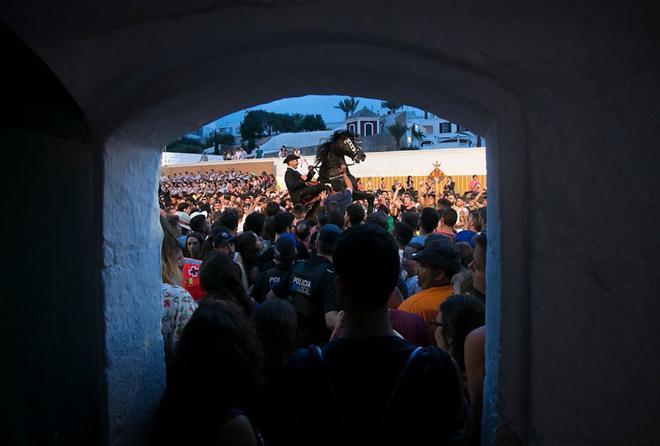 Una cabalgata entre la multitud durante los Jocs des Pla, juegos ecuestres celebrados en el puerto lleno de gente durante el tradicional festival de Sant Joan (San Juan) en la ciudad de Ciutadella, en la isla balear de Menorca, el día de San Juan.