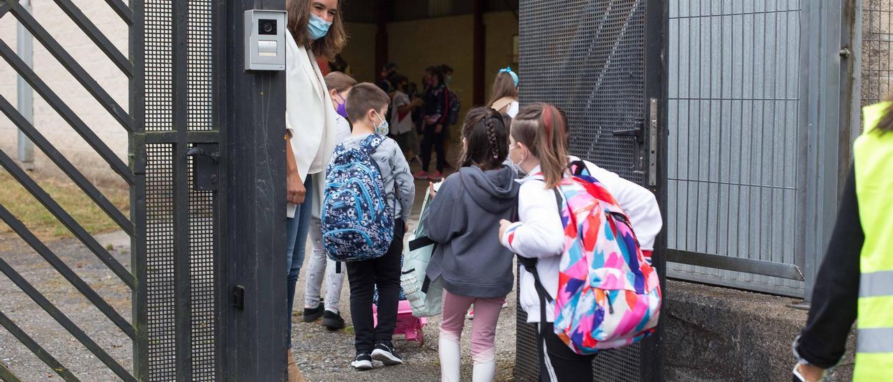 Varios niños y niñas entran al colegio.