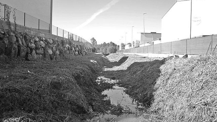 El río Alvedosa rodeado de naves a su paso por el polígono industrial de Amoedo, en Pazos.