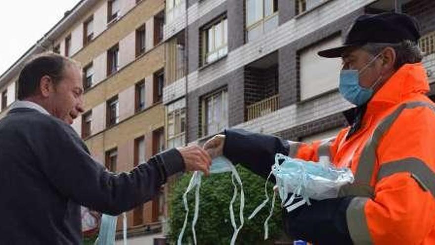 Un voluntario de Protección Civil, repartiendo mascarillas en El Berrón.