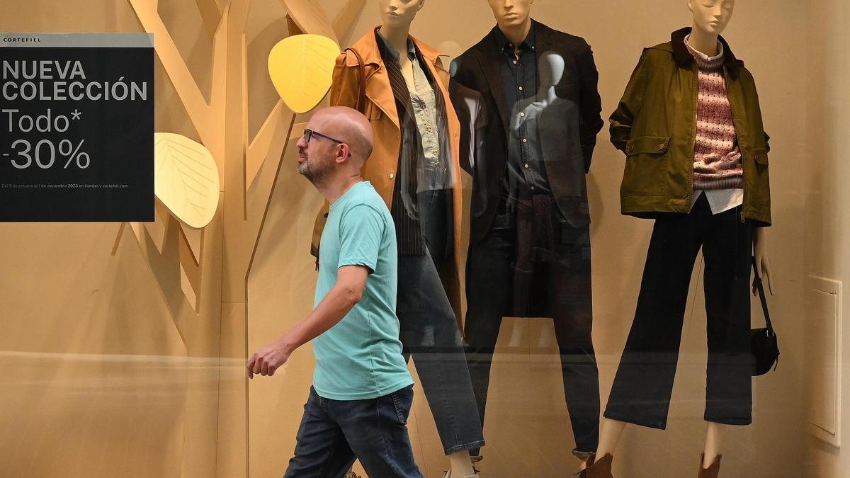 Un hombre, en manga corta, pasa este lunes por delante de un establecimiento de moda de Castelló con el escaparate centrado ya en la ropa de abrigo.