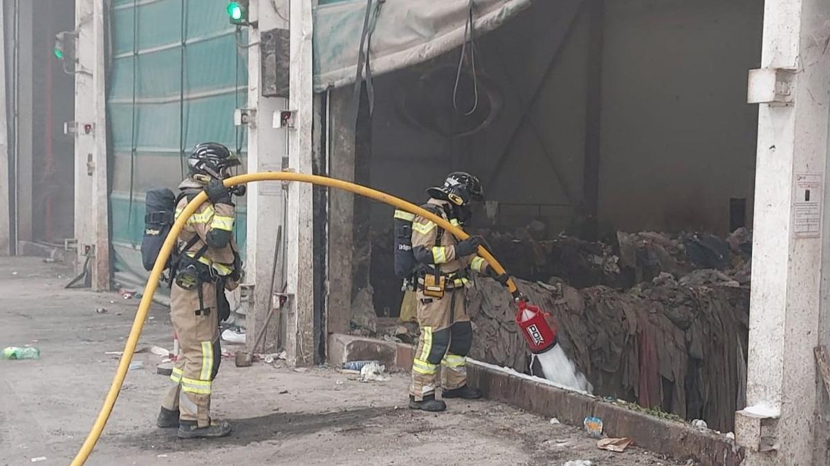 Dos efectivos de bombero intervienen con una manguera en el vertedero