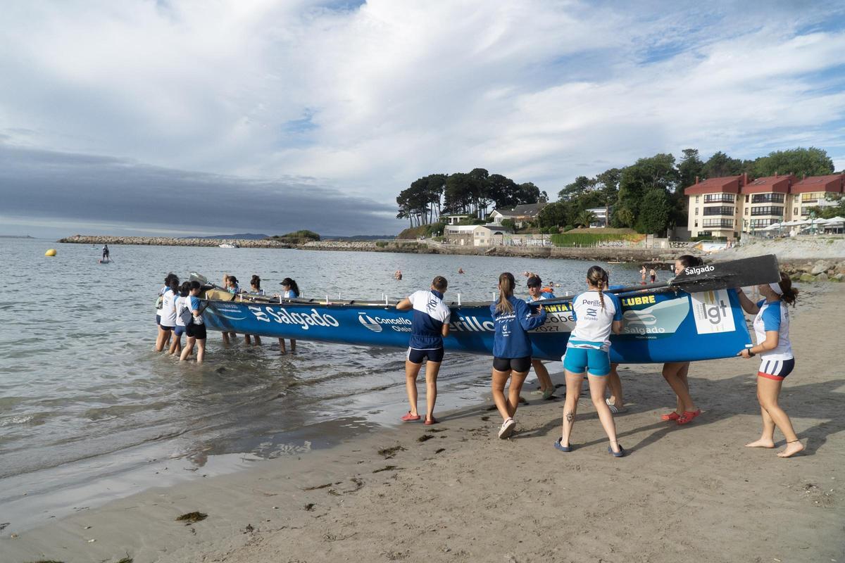 La tripulación carga su trainera en la orilla del arenal oleirense.