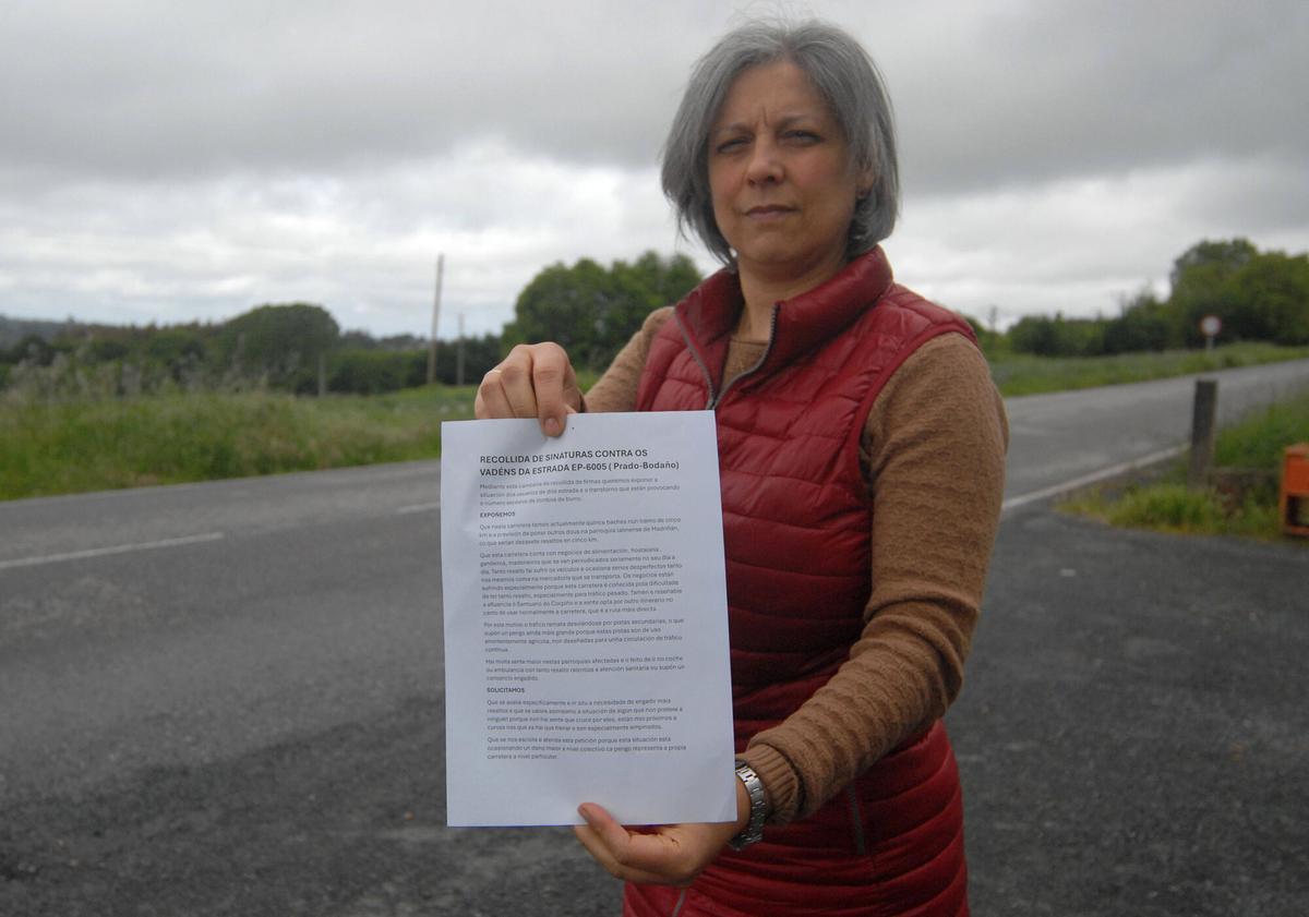 Una vecina muestra el documento para la recogida de firmas.