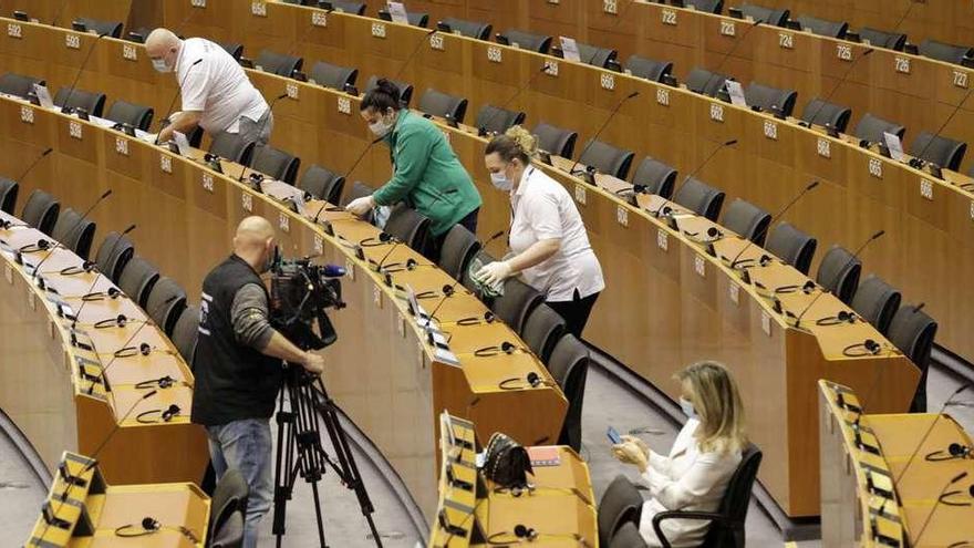 Limpiadores del Parlamento Europeo desinfectan los escaños antes del arranque de la sesión plenaria.