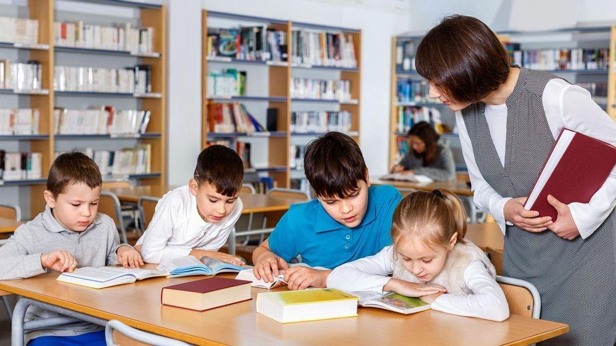 Una profesora con sus alumnos en una biblioteca escolar.