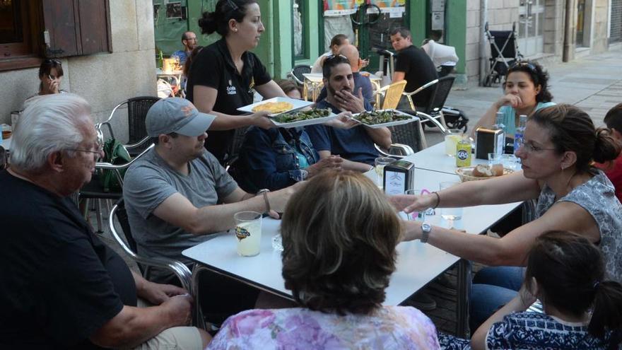 Una camarera sirve una mesa con comensales en Vilagarcía. // Noé Parga