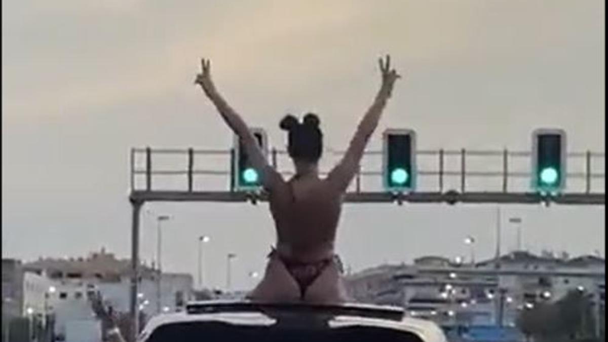 Chica en bikini con medio cuerpo fuera del coche