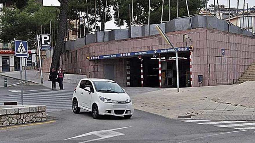 Un vehículo circulando ante la entrada de los aparcamientos.