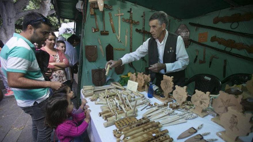 El artesano José Díaz vende pitos de caña a dos niñas, ayer en la feria de San Gregorio.