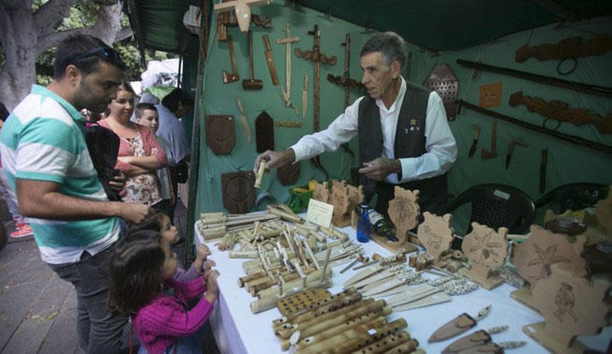 El artesano José Díaz vende pitos de caña a dos niñas, ayer en la feria de San Gregorio.