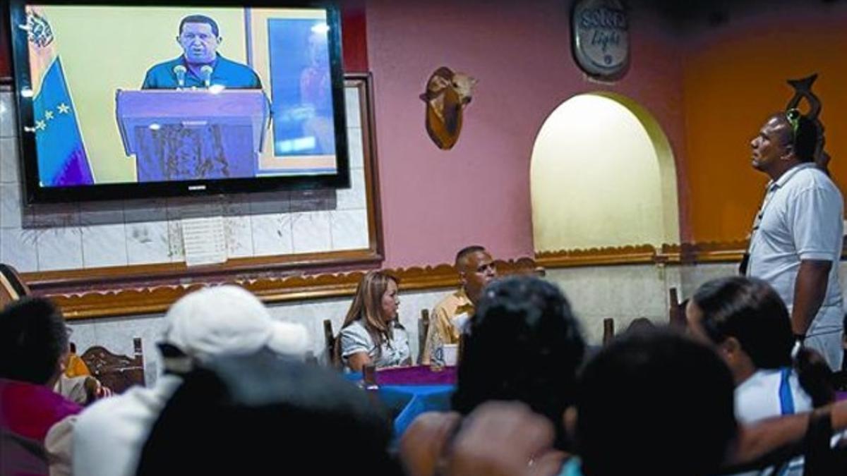Clientes de un bar en Caracas siguen el discurso televisado de Chávez, ayer.