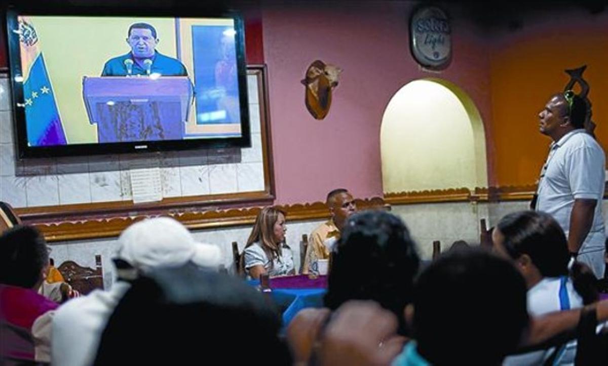 Clientes de un bar en Caracas siguen el discurso televisado de Chávez, ayer.