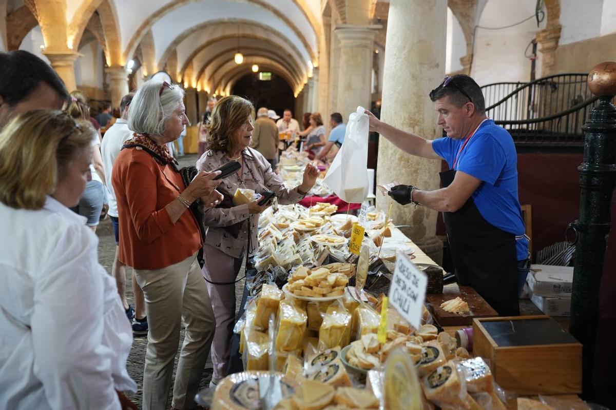 Unas clientas adquieren uno de los quesos de la feria.