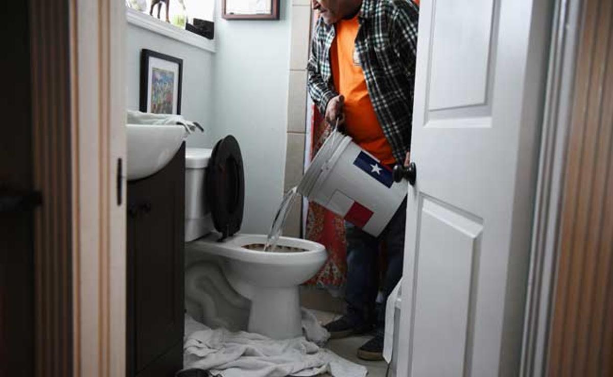 Un hombre utiliza un cubo de agua para limpiar su retrete.