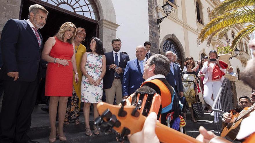 Susana Díaz, el alcalde de Adeje, José Miguel Rodríguez Fraga (i), y Carolina Darias (d), escuchan a la tuna de la Universidad de La Laguna, ayer.