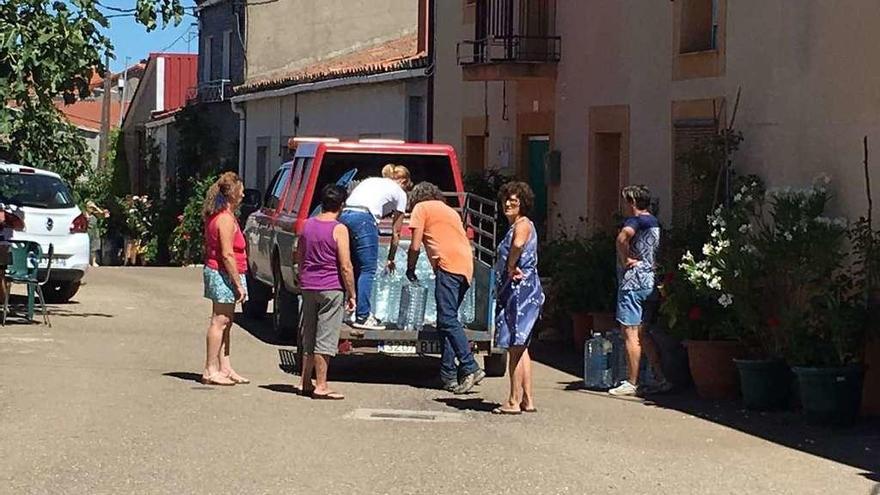 Vecinos de Arcillera recogen las garrafas de agua de vehículo.
