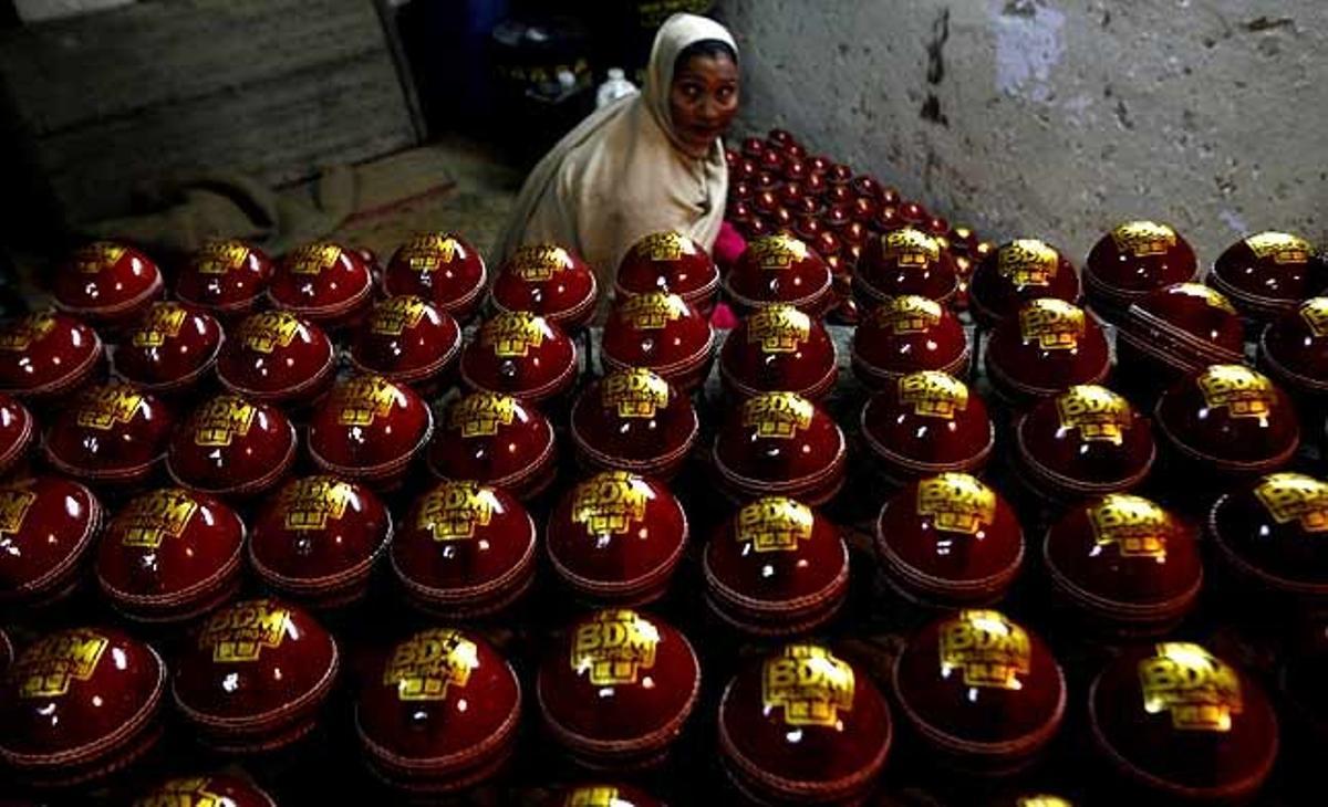 Una treballadora neteja pilotes de criquet abans que siguin embalades en una fàbrica a Meerut, a 80 quilòmetres al nord-est de Nova Delhi (Índia).