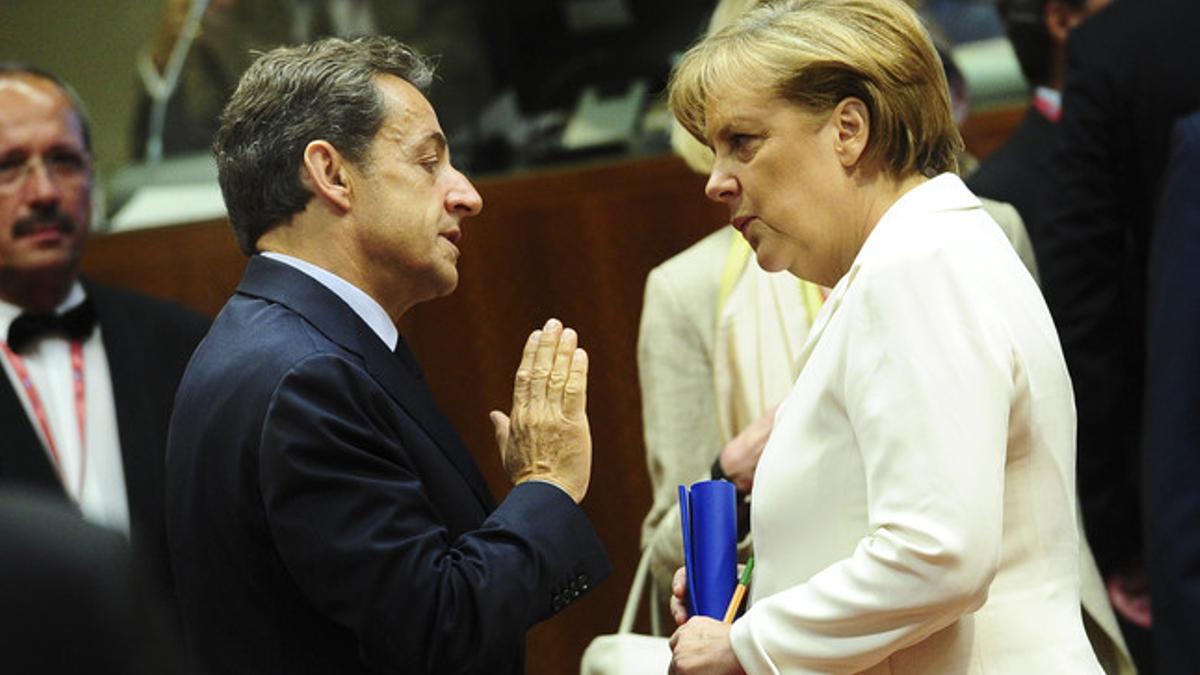 El presidente francés, Nicolas Sarkozy, habla con la cancillera alemana, Angela Merkel, este viernes, durante la cumbre de la UE en Bruselas.
