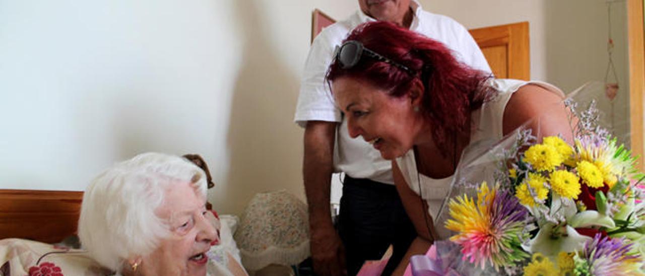 La concejal de Antigua, Deborah Edginton, entrega un ramo de flores a Dina Lacy. Detrás, el alcalde, Cazorla.